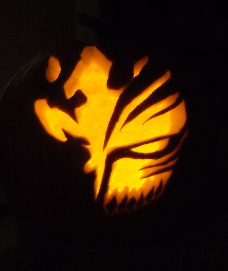 a carved pumpkin with an animal's head in the center and leaves on it