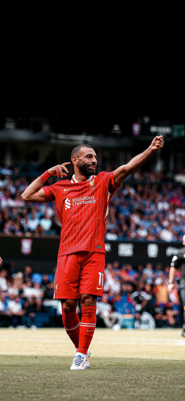 a man in red uniform standing on top of a field with his arms up and hands out