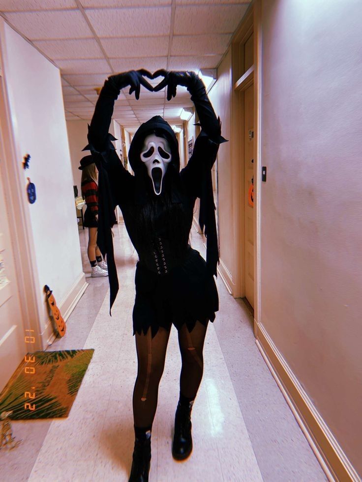 a woman dressed in black and white is walking down the hallway with her hands up