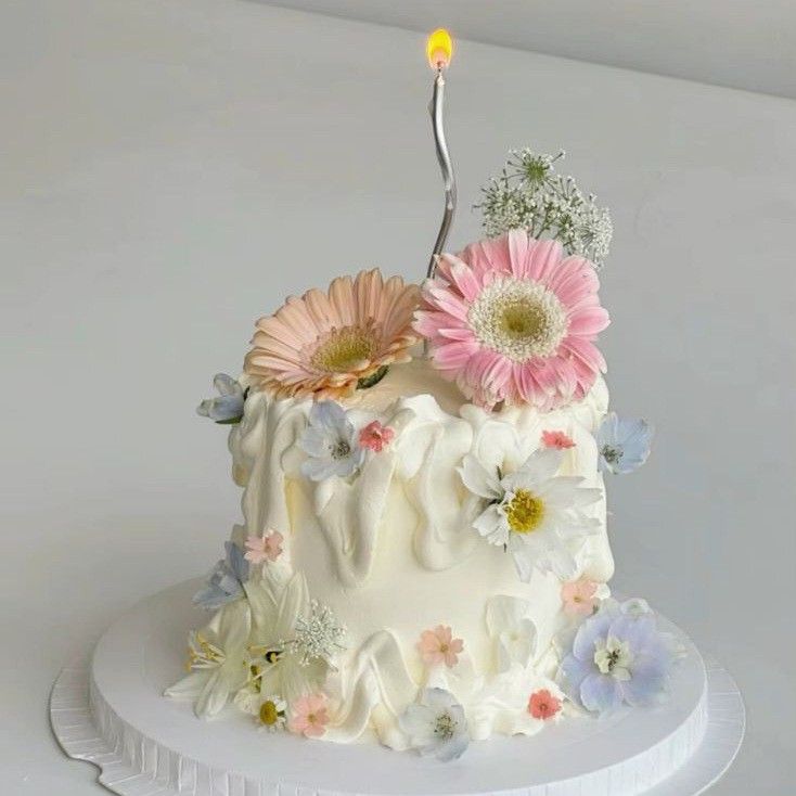 a white cake with flowers and a single candle