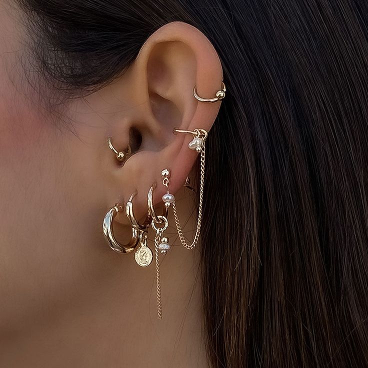 a close up of a person wearing ear rings with chains and moon charms on them