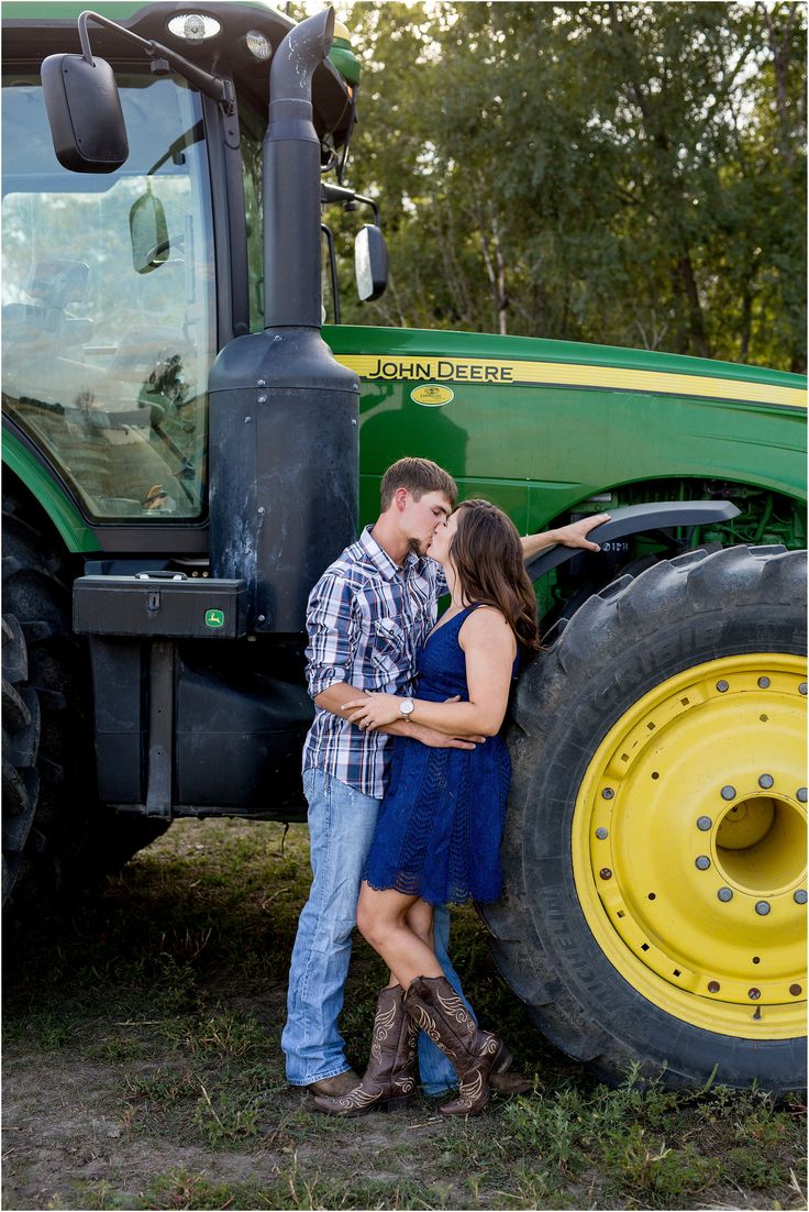 a man and woman standing in front of a tractor with their arms around each other