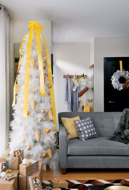 a living room decorated for christmas with a white tree and yellow ribbon on the top