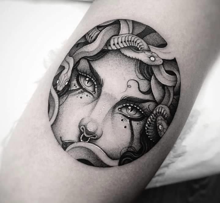 a woman's face in a circle tattoo on the arm