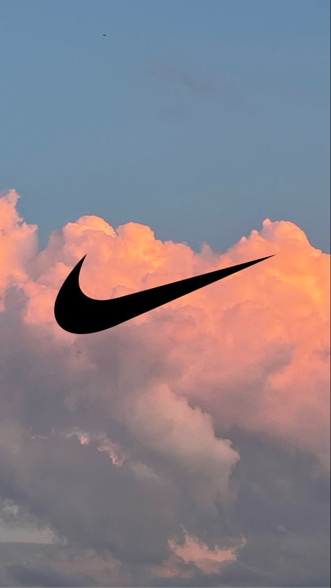 the silhouette of a nike logo against a pink and blue sky with clouds in the background