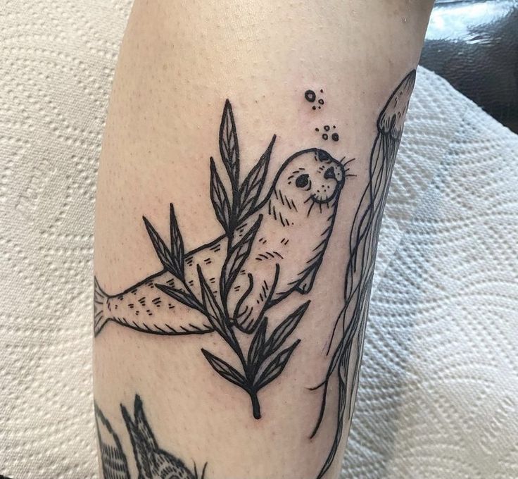 a tattoo on the leg of a woman with an otter and bamboo tree in it