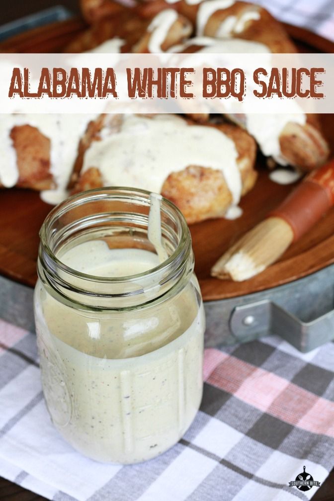 a jar filled with white bbq sauce sitting on top of a table next to bread