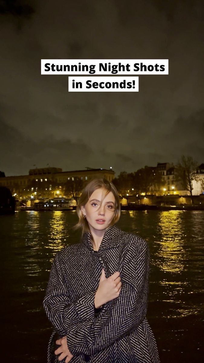 a woman standing in front of the water at night