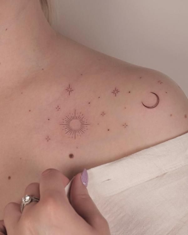 a woman's chest with stars and a crescent tattoo on her left side shoulder