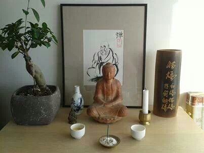 there is a buddha statue on the table next to two vases and a potted plant