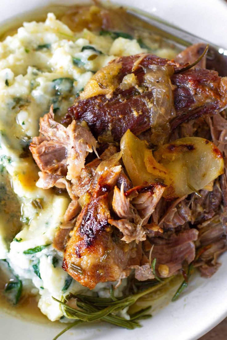 a white plate topped with mashed potatoes covered in meat and vegtables