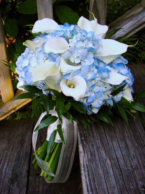 a bouquet of blue and white flowers on a wooden bench