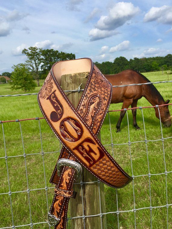 a horse grazing behind a fence with a leather belt on it