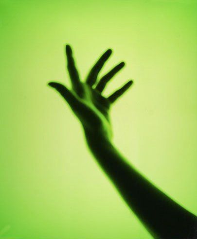 a person's hand reaching up into the air in front of a green background