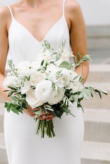 a woman holding a bouquet of white flowers