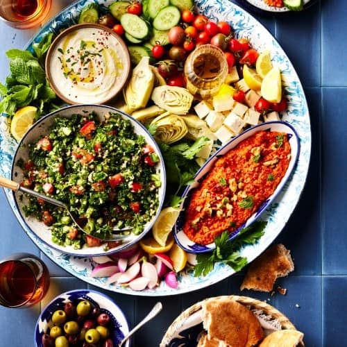 a platter filled with lots of different types of food next to wine glasses and plates