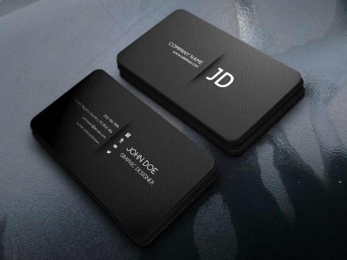 two black business cards sitting on top of a gray surface with the letter d in white