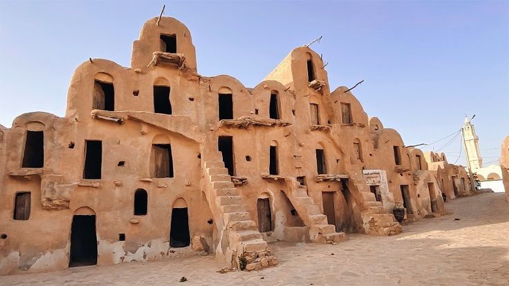 an old adobe building in the desert with steps leading up to it's windows