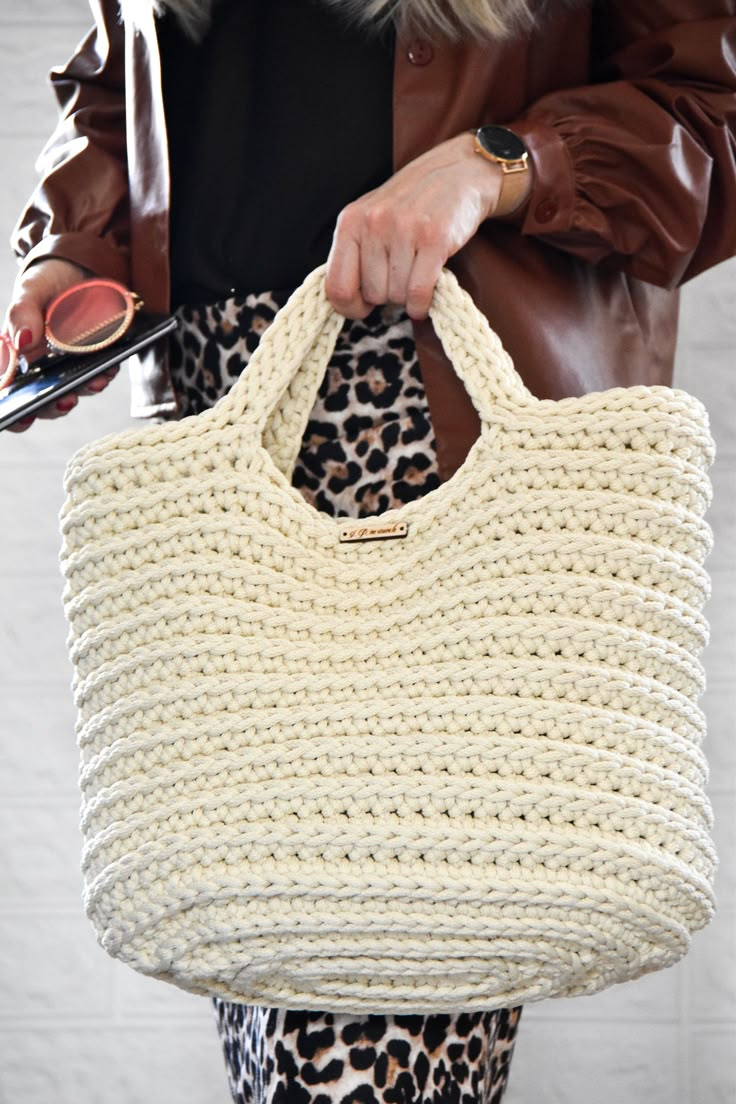 a woman holding a large white knitted bag