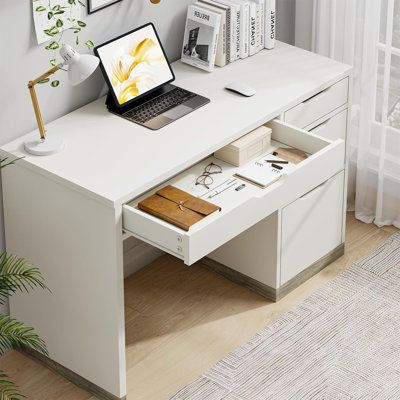 a laptop computer sitting on top of a white desk next to a potted plant