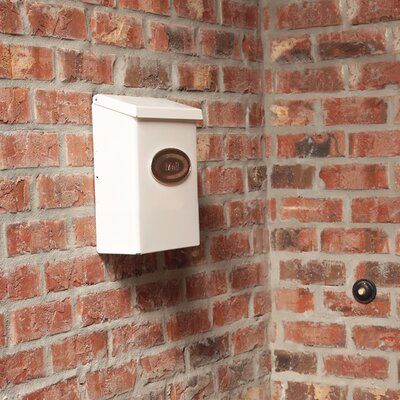 a brick wall with a white box mounted to it's side next to a toilet paper dispenser