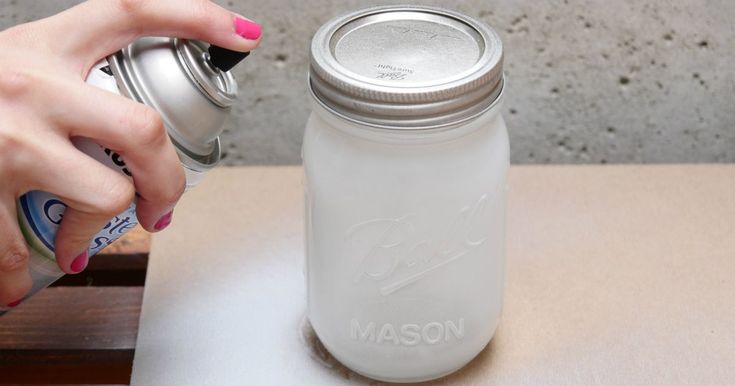 a person is spraying something into a mason jar