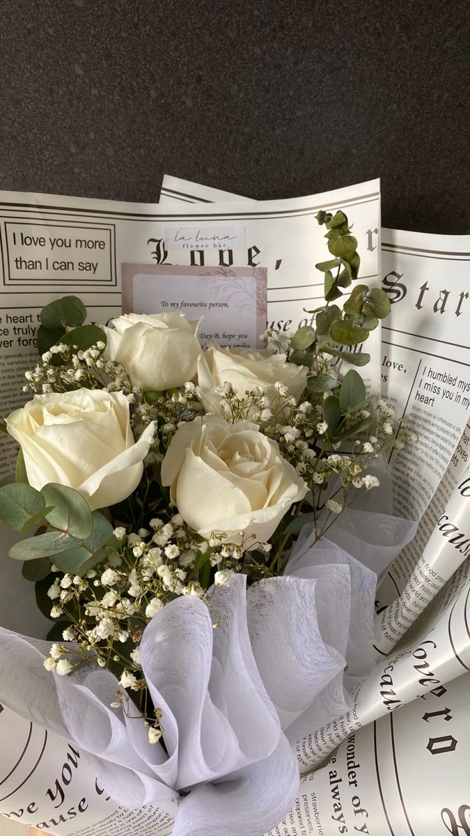 a bouquet of white roses sitting on top of newspapers