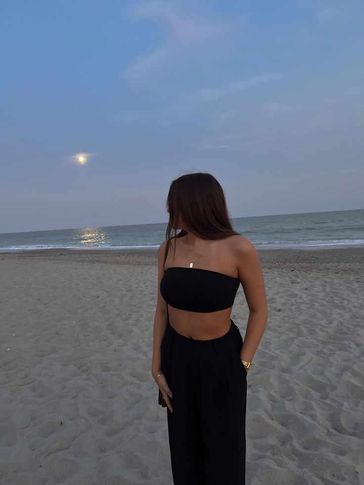 black bandeau top, gold jewelry, black trousers, beach fit, summer, vacation fit Black Beach Dinner Outfit, Dark Vacation Outfits, Black Pants Beach Outfit, Late Night Beach Outfit, Black Beach Pants Outfit, Bandeau Top Outfits Summer, Flowy Black Pants Outfit, Black Bandeau Top Outfit, Black Bandeau Outfit