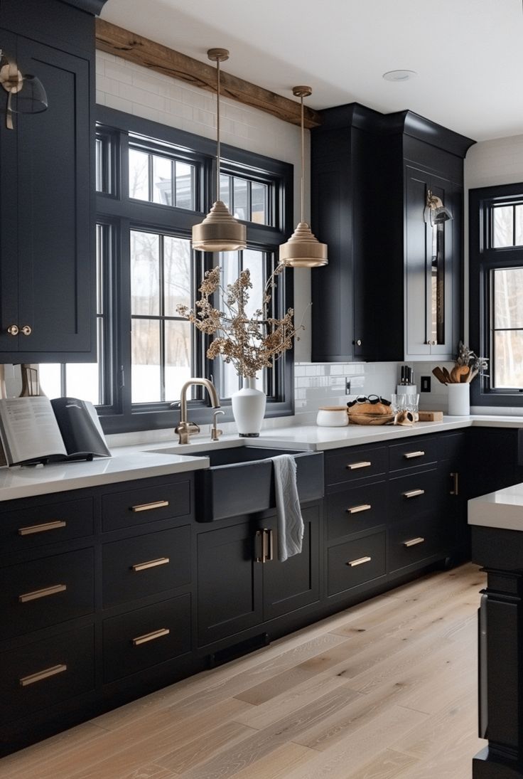 a large kitchen with black cabinets and white counter tops, wooden flooring and pendant lights hanging from the ceiling