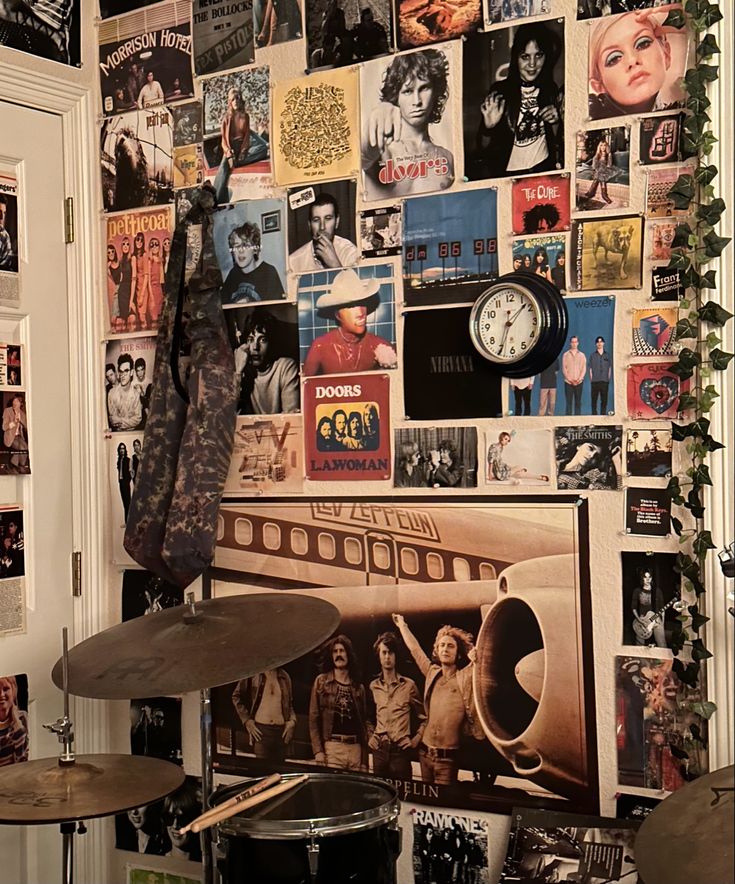 a wall covered in posters and pictures next to drums