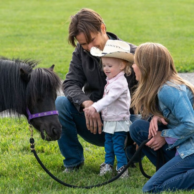 two women and a child petting a small horse