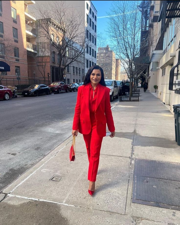 a woman in a red suit is walking down the street