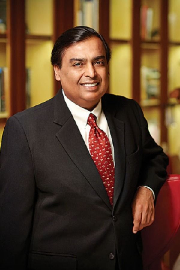 a man in a suit and tie smiling for the camera with bookshelves behind him