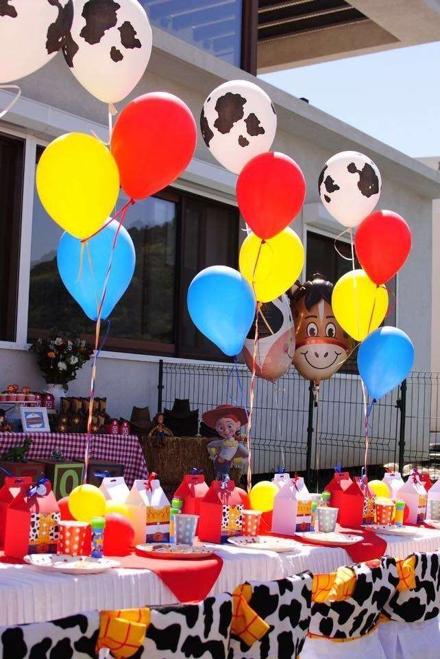 a table topped with lots of balloons next to a cow head on top of a building