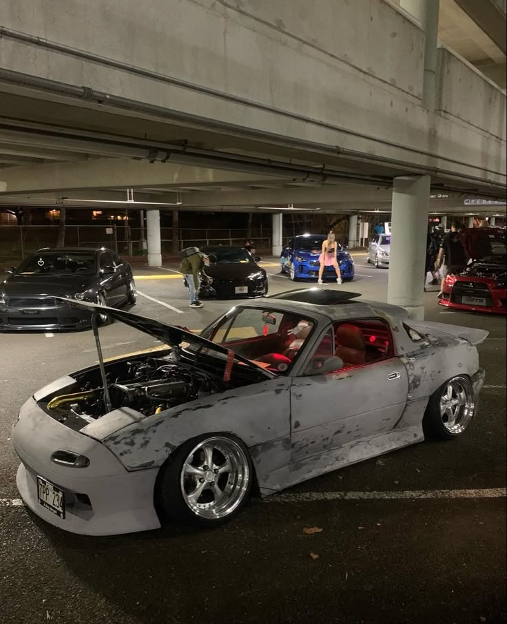 a car that is parked in a parking lot with its hood up and the engine on top of it