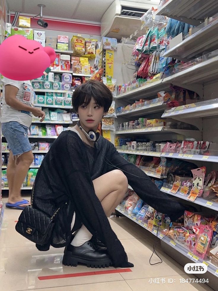 a woman sitting on the ground in front of a store shelf with her legs crossed