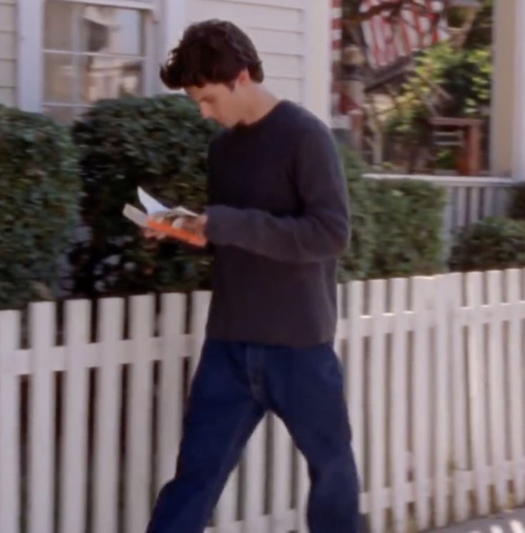 a man walking down the street while reading a book