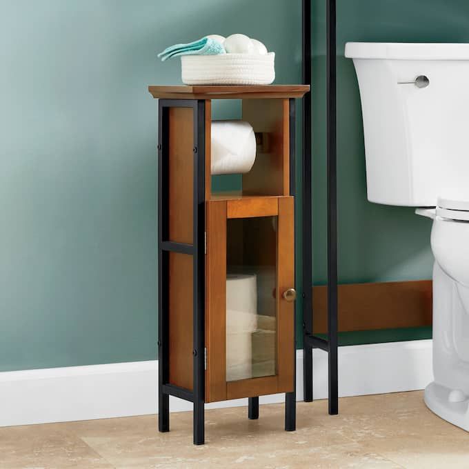 a wooden cabinet next to a white toilet in a room with blue walls and tile flooring