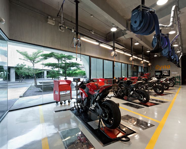 motorcycles are lined up on display in a large room with lots of windows and lights