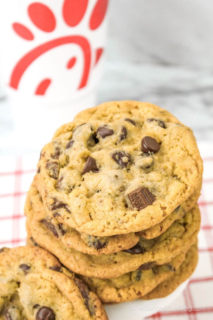 chocolate chip cookies are stacked on top of each other in front of a coffee cup