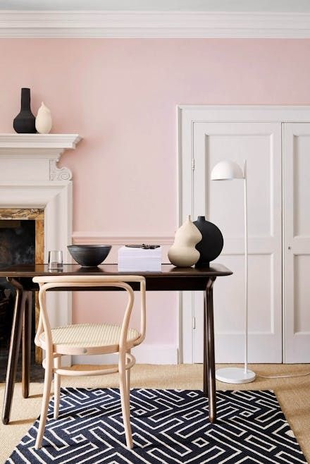 a living room with pink walls and white trim on the fireplace mantel, black and white accents