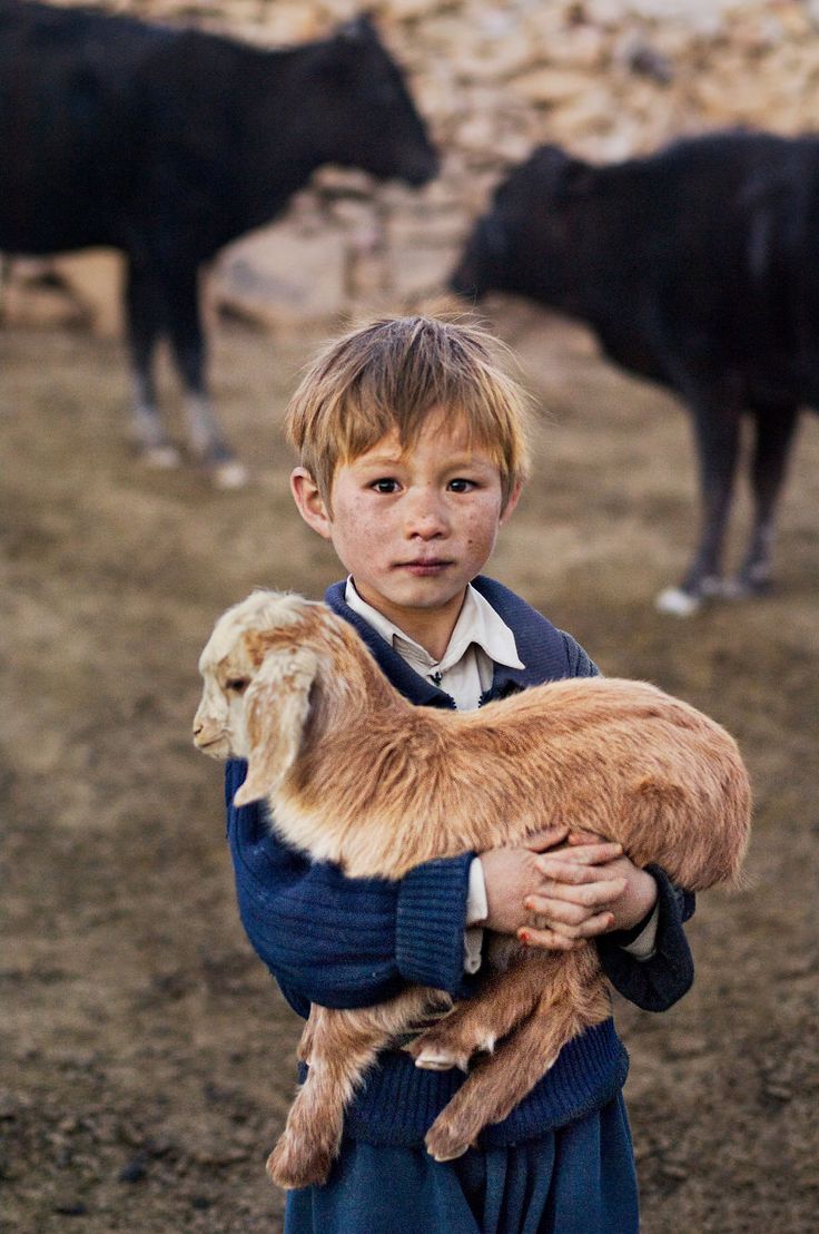 a young boy holding a goat in his arms