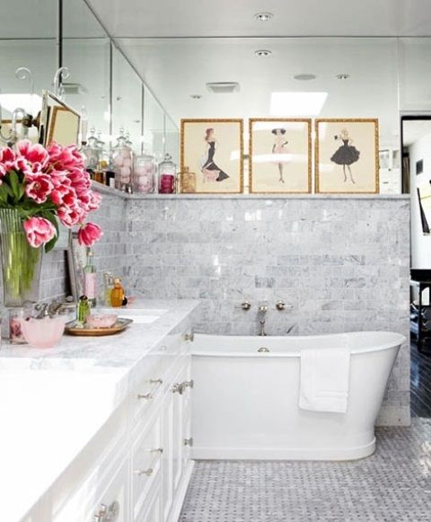 a white bath tub sitting inside of a bathroom next to a sink and toilet covered in pink flowers