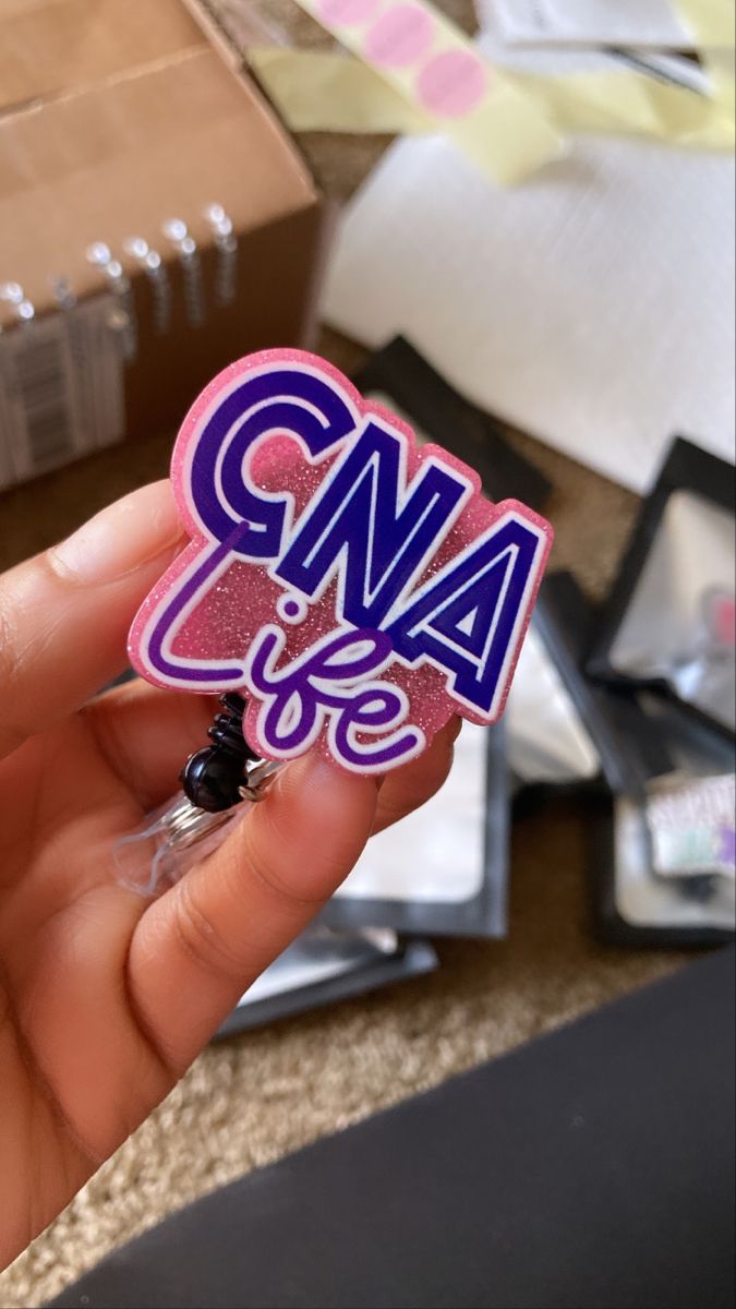 someone holding up a sticker with the word cma in purple and blue on it