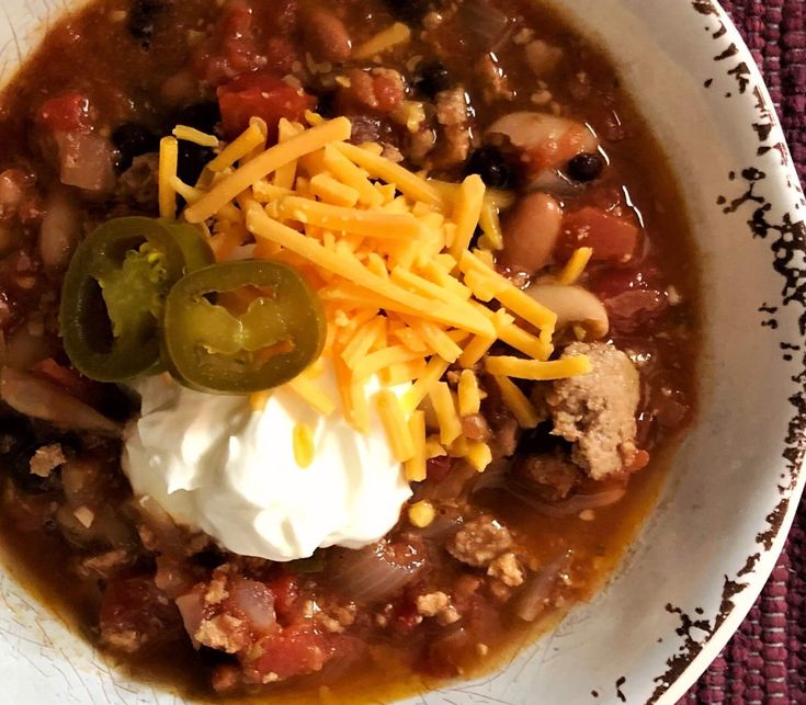 a white bowl filled with chili and sour cream