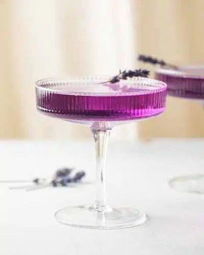 two glasses filled with purple liquid sitting on top of a white table next to each other