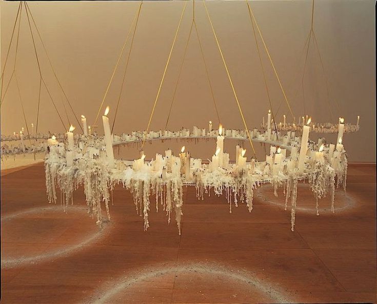 a group of white candles sitting on top of a wooden table covered in icicles