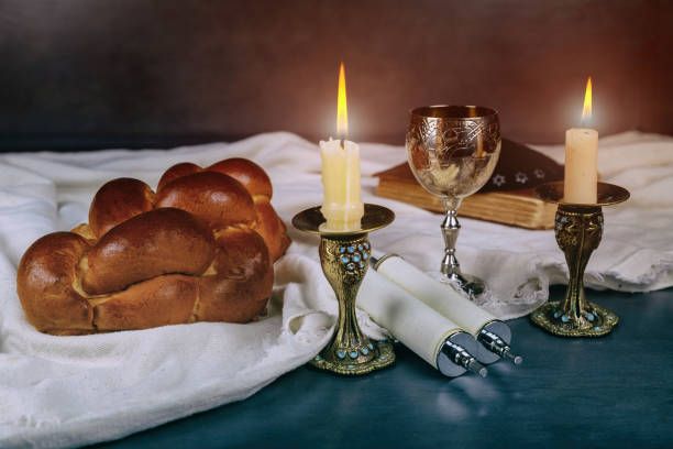 bread and candles on a table next to a cloth with two wine goblets