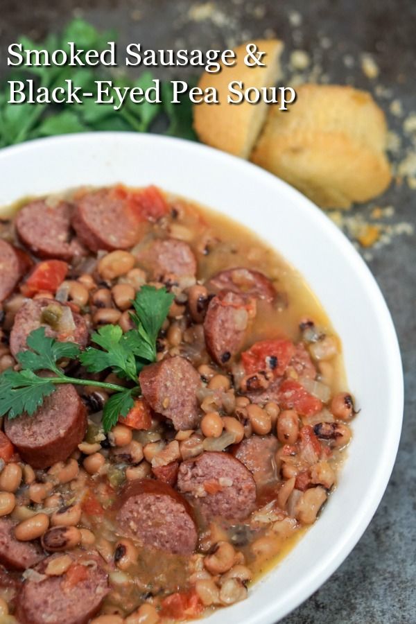 a bowl of smoked sausage and black - eyed pea soup with bread on the side