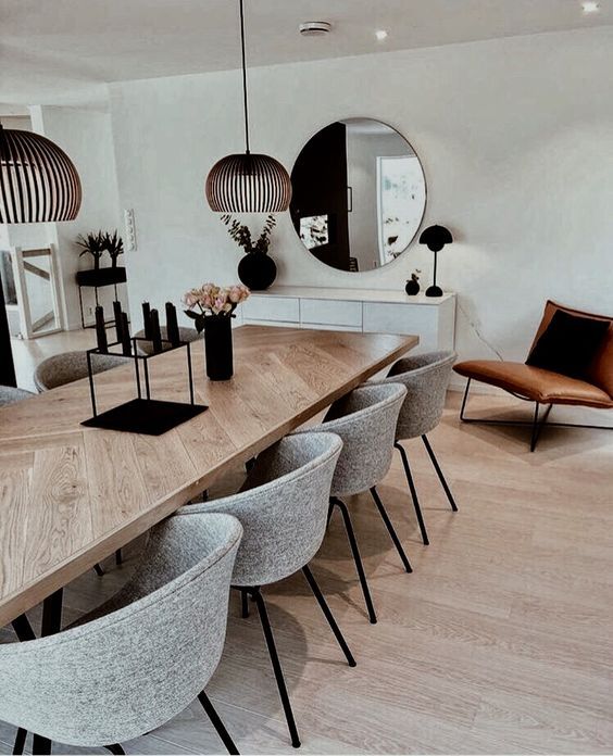 a dining room table with chairs and mirrors on the wall above it, in front of a mirror